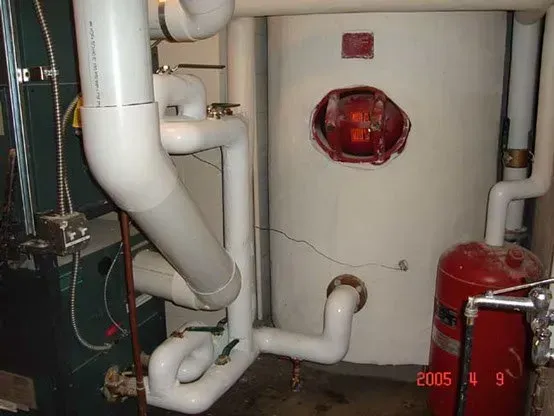 White pipes and tank in utility room. Boiler, expansion tank.