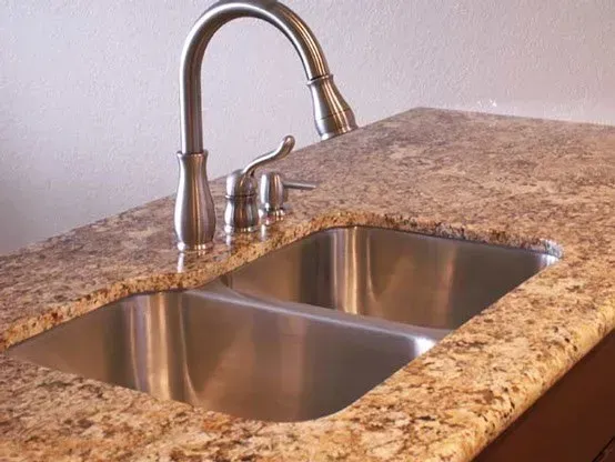 Stainless steel double sink with faucet in granite countertop.