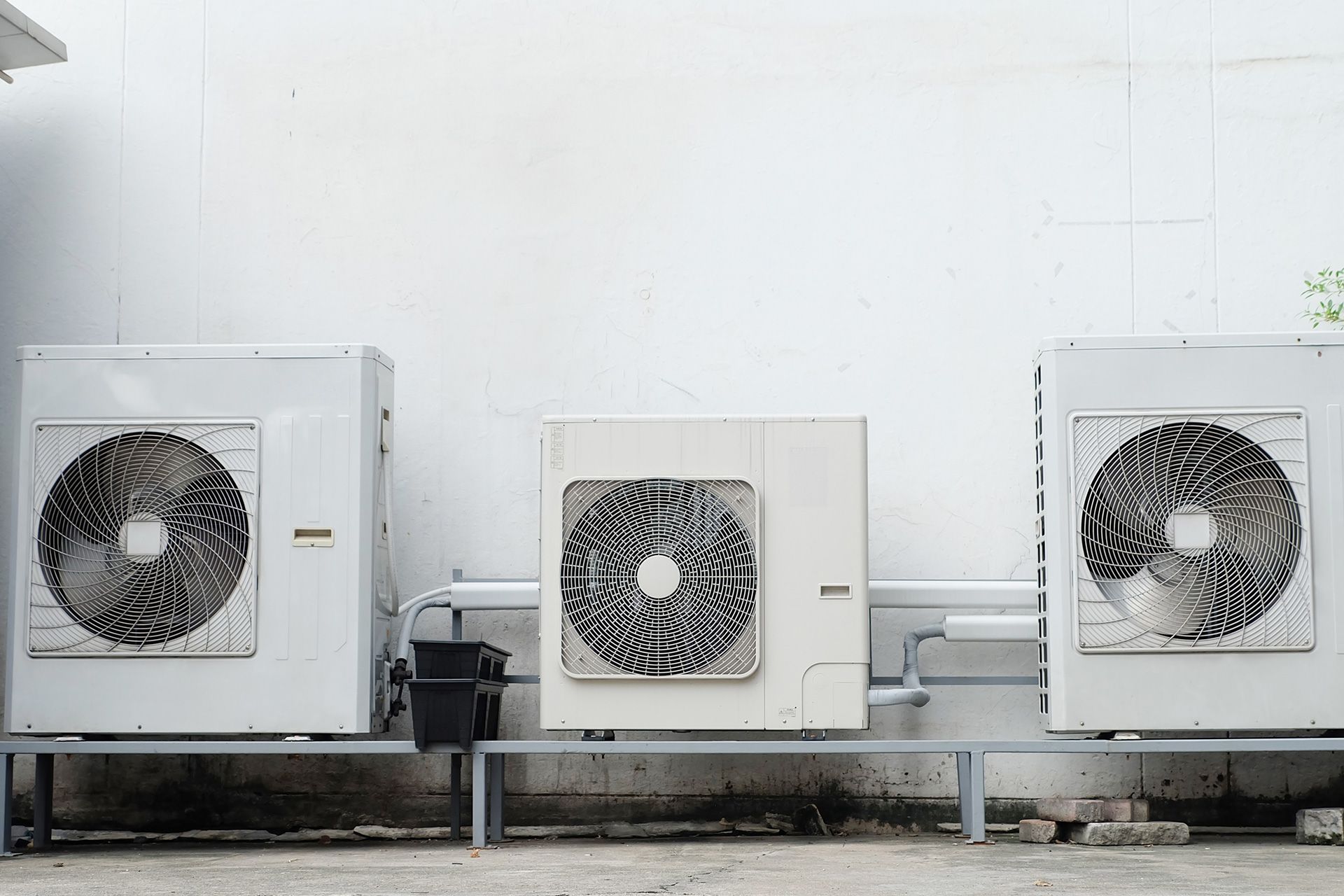 Three air conditioners are sitting next to each other on the side of a building.