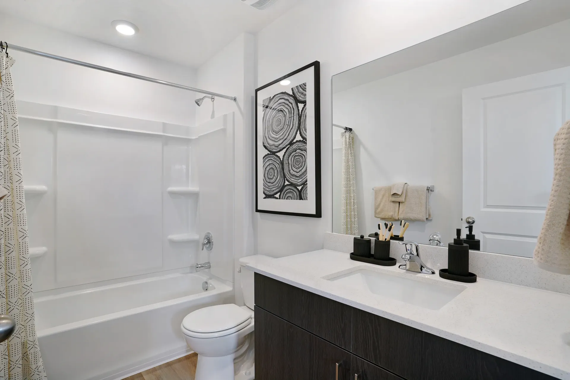 Modern bathroom with a bathtub, toilet, vanity, and mirror at Little Valley, offering  pet-friendly apartments in Magna, UT.