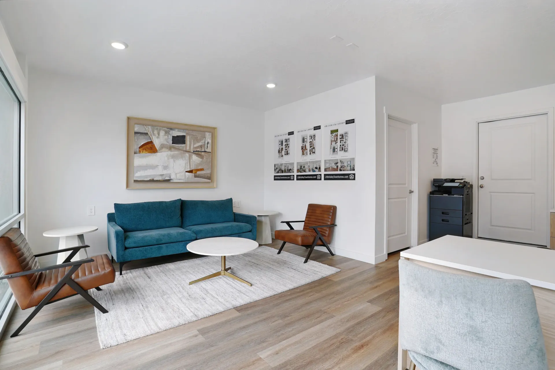 A modern living room with a teal couch, leather accent chairs, and a coffee table at Little Valley, offering apartments in Magna, UT.