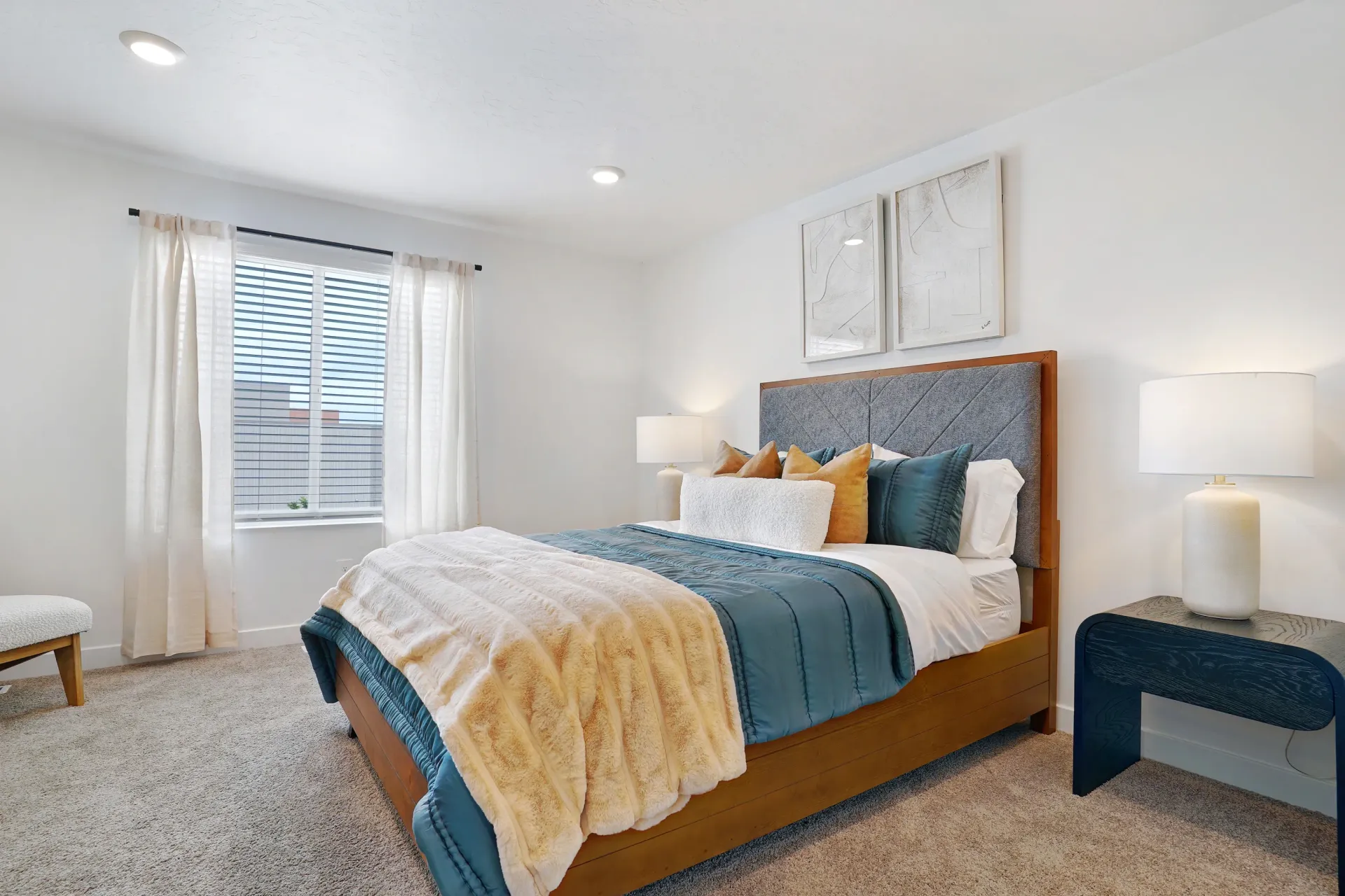 A bedroom with a queen-size bed, teal bedding, and two framed pictures on the wall at Little Valley, offering  pet-friendly apartments in Magna, UT.