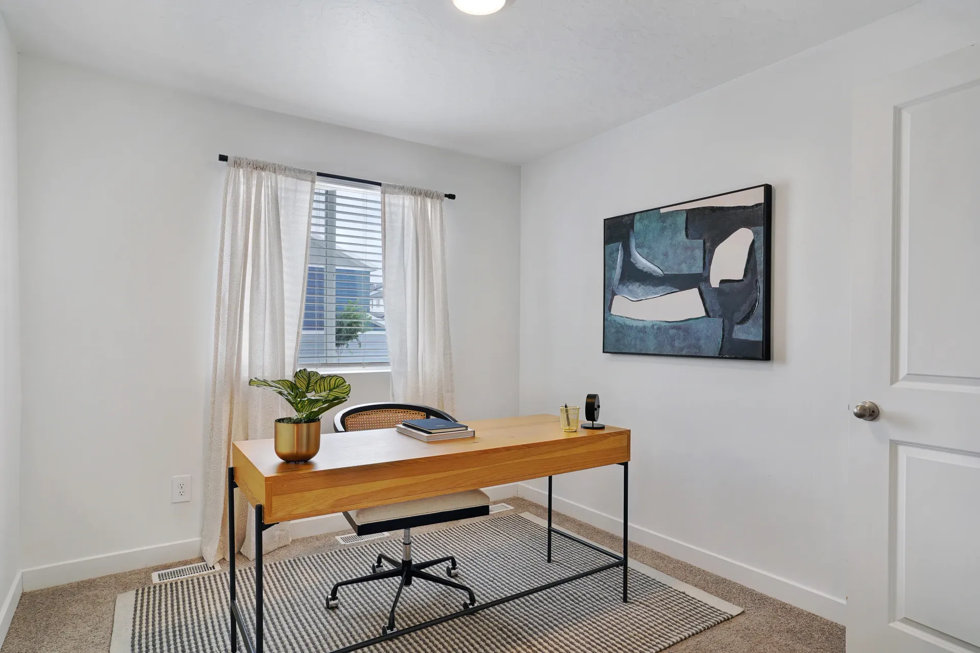 Home office with a wooden desk, office chair, and a potted plant at Little Valley, offering  pet-friendly apartments in Magna, UT.