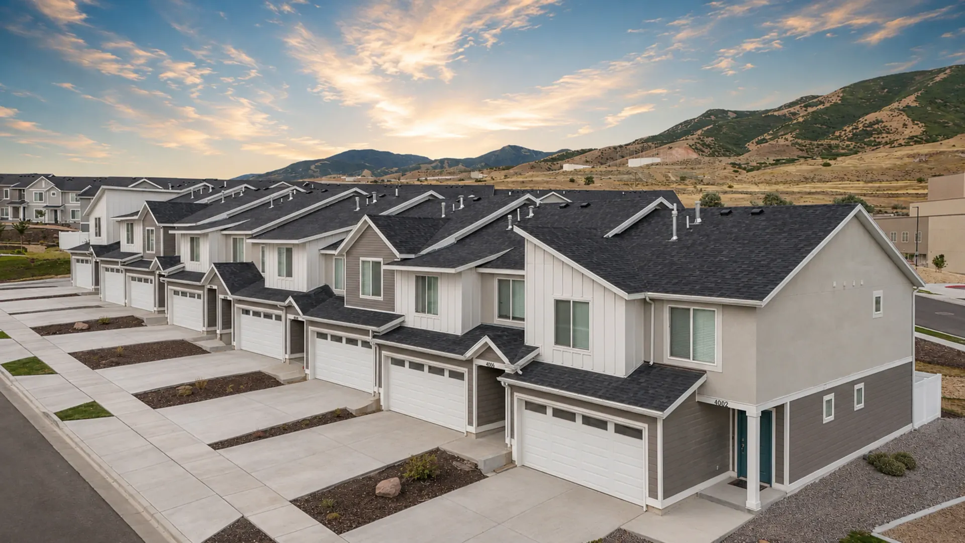 Row of modern townhomes with garages and driveways in front, mountains in the background at Little Valley, offering apartments in Magna, UT.