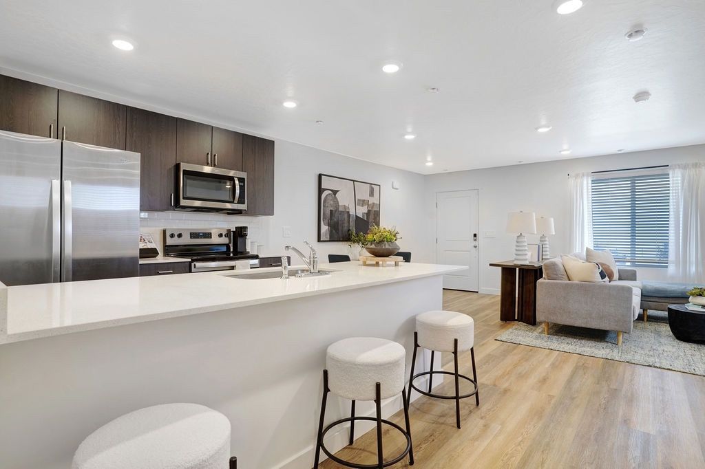 Open-concept kitchen with a white island, stainless-steel appliances, and a living area.