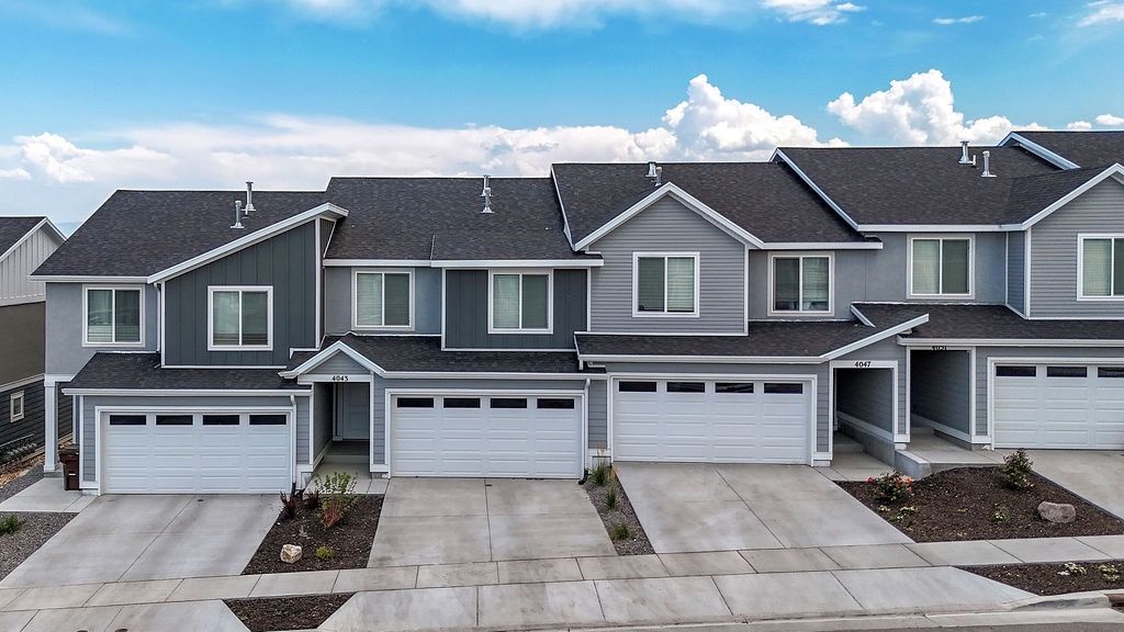 Row of modern townhouse-style apartments with attached two-car garages and paved driveways.