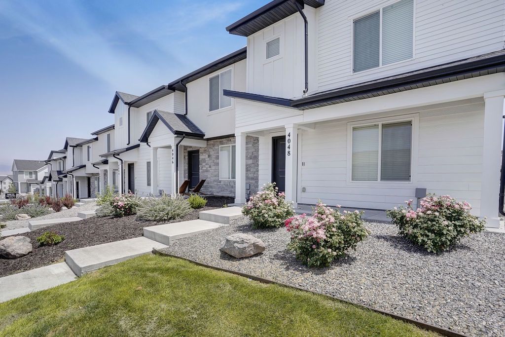 Row of white townhome-style apartment buildings with landscaped front yards and steps.