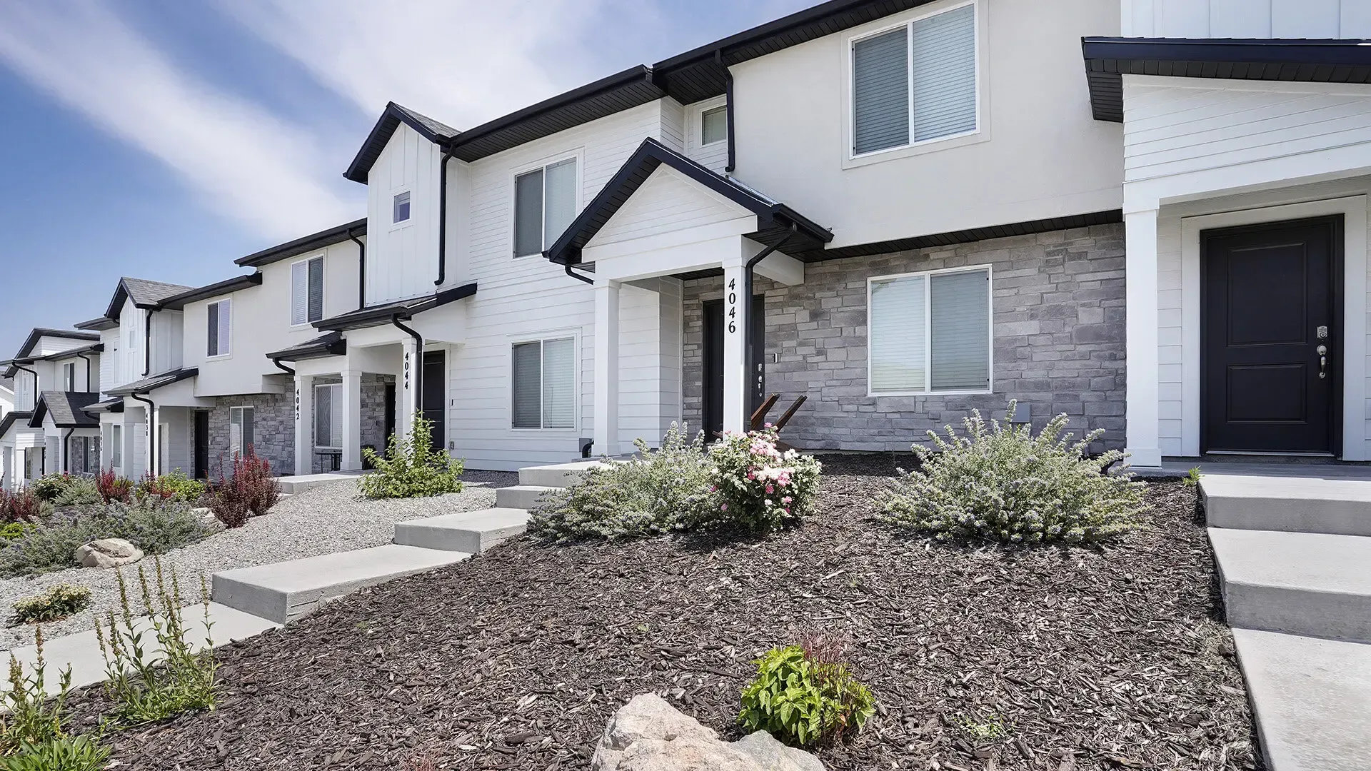 Exterior of modern townhomes with white siding and stone accents at Little Valley, offering apartments in Magna, UT.