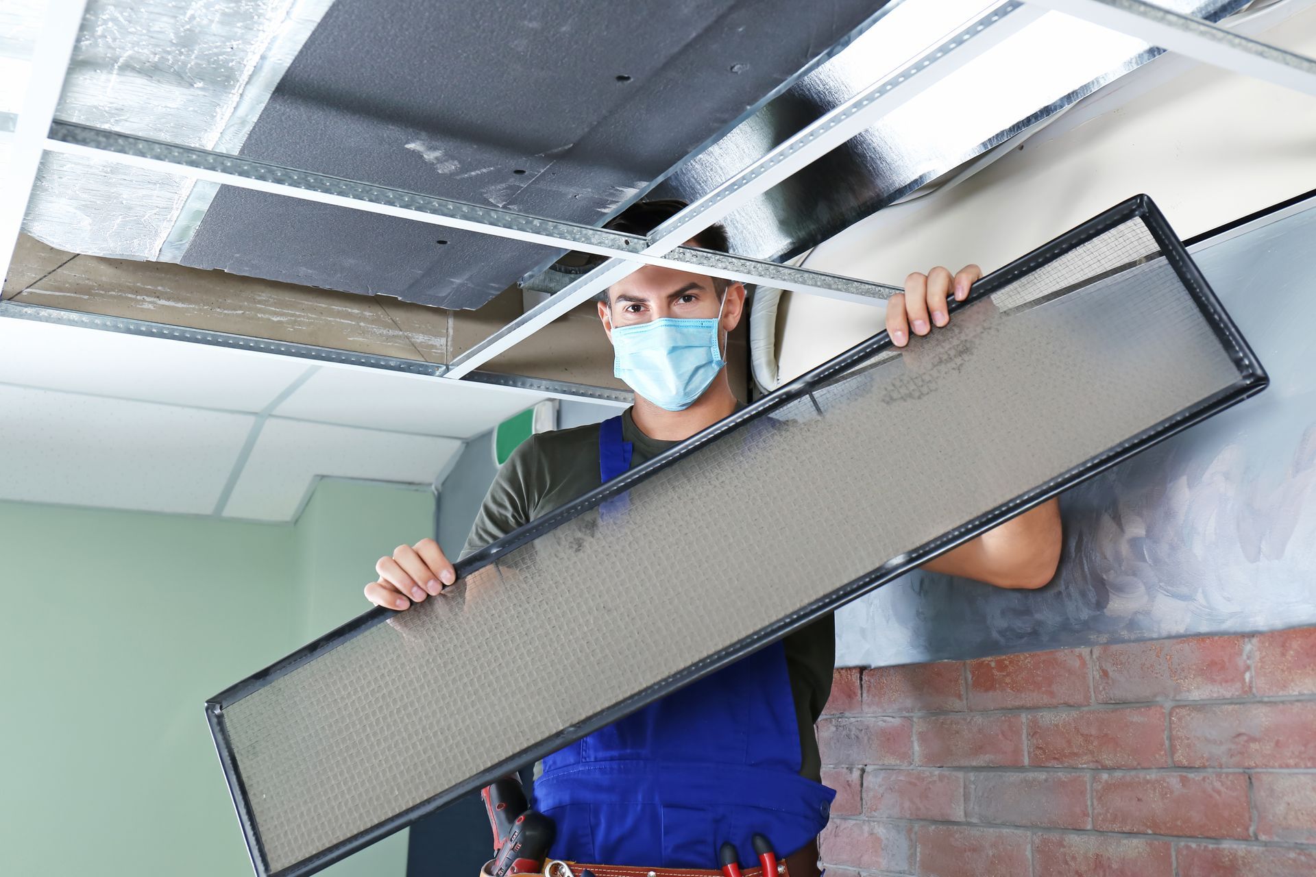 an hvac technitian removes the air filter from a commercial airvent, the filter is dusty highlighting the question How Often Should Commercial Airvents Be Cleaned and Inspected
