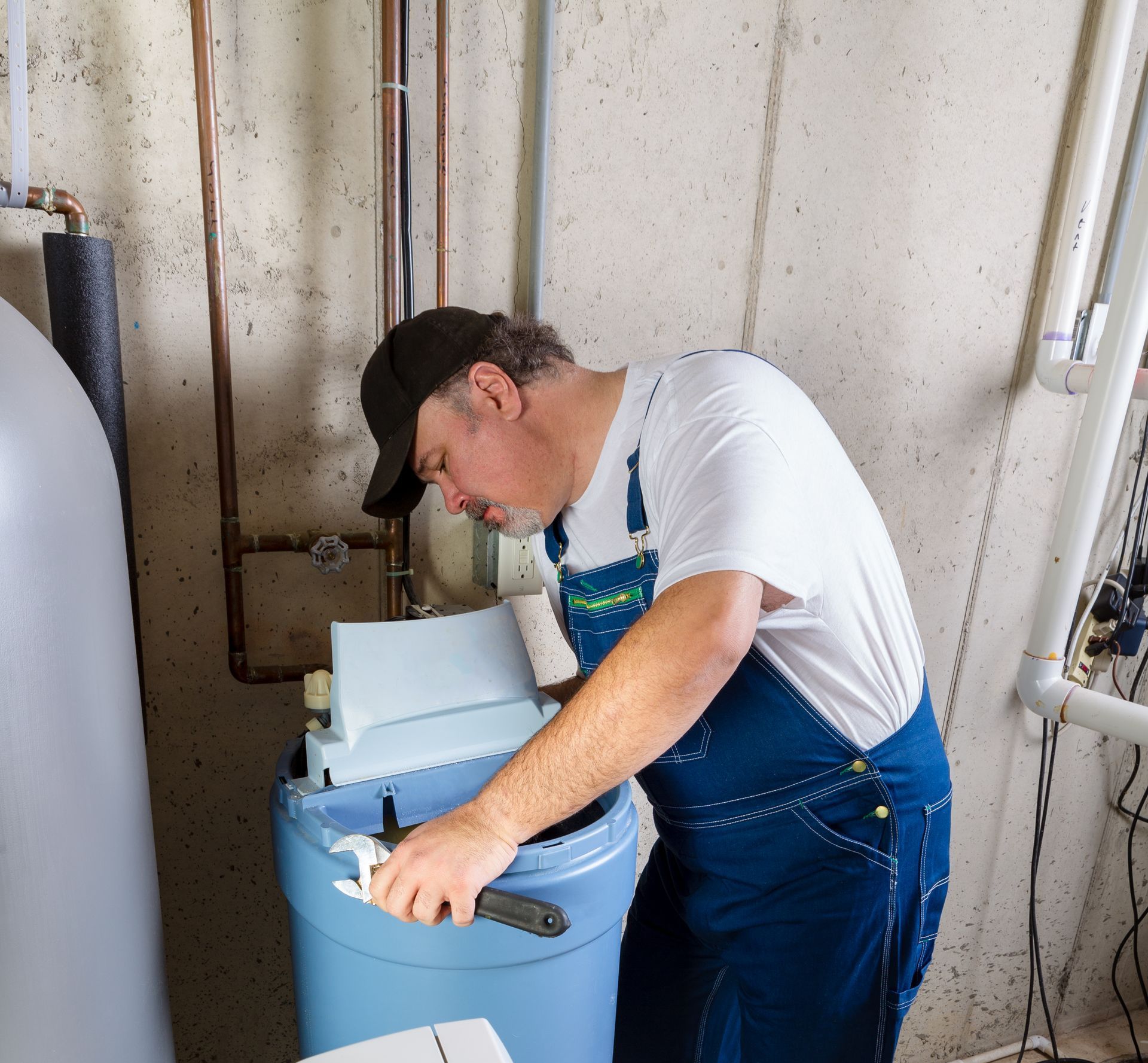 a plumber reaches inside the water softener to install it