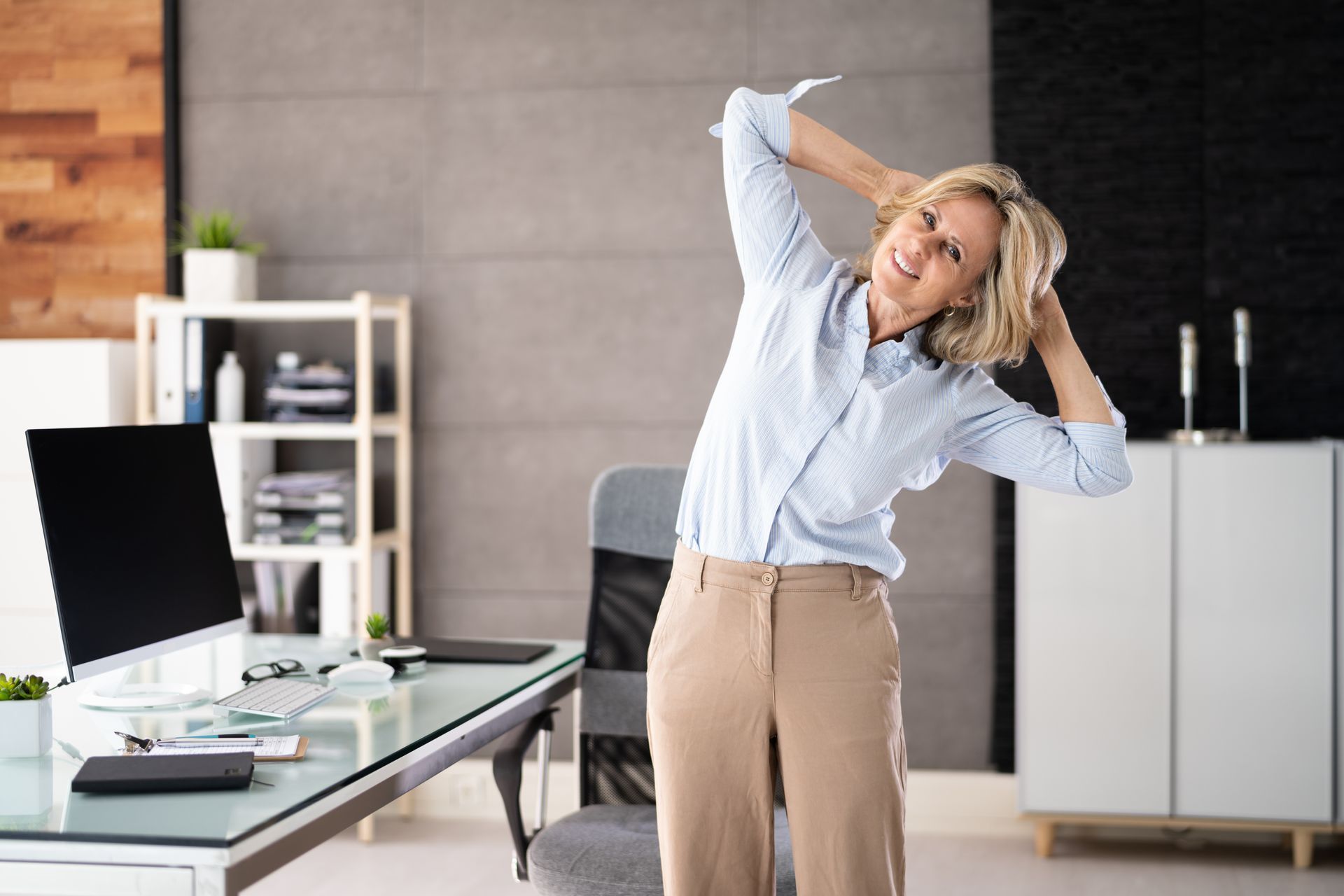 A woman is stretching her torso to help prevent and alleviate pain from working from home