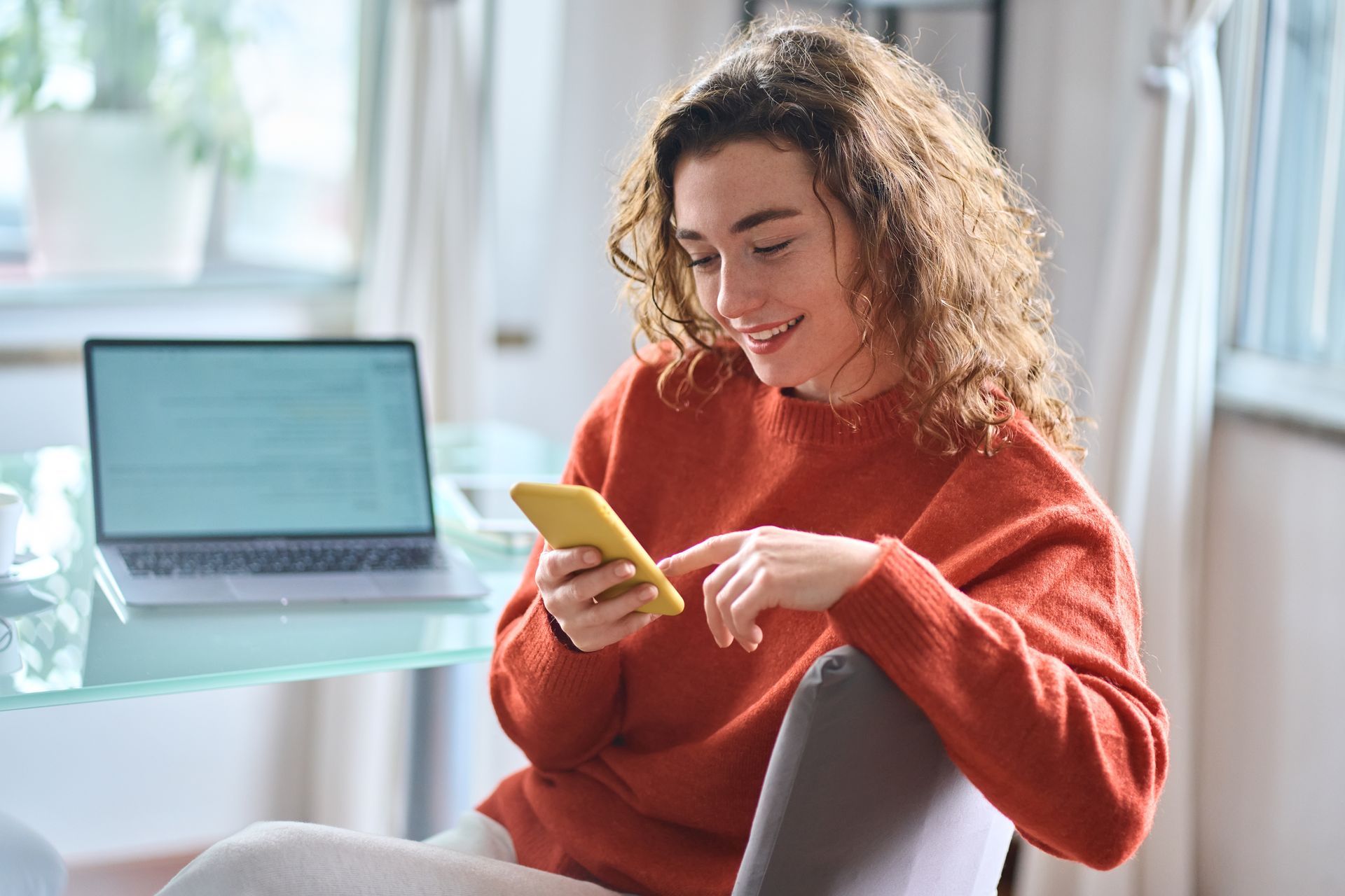 a woman is sitting in a chair looking at her cell phone, building consumer engagement for brand affinity