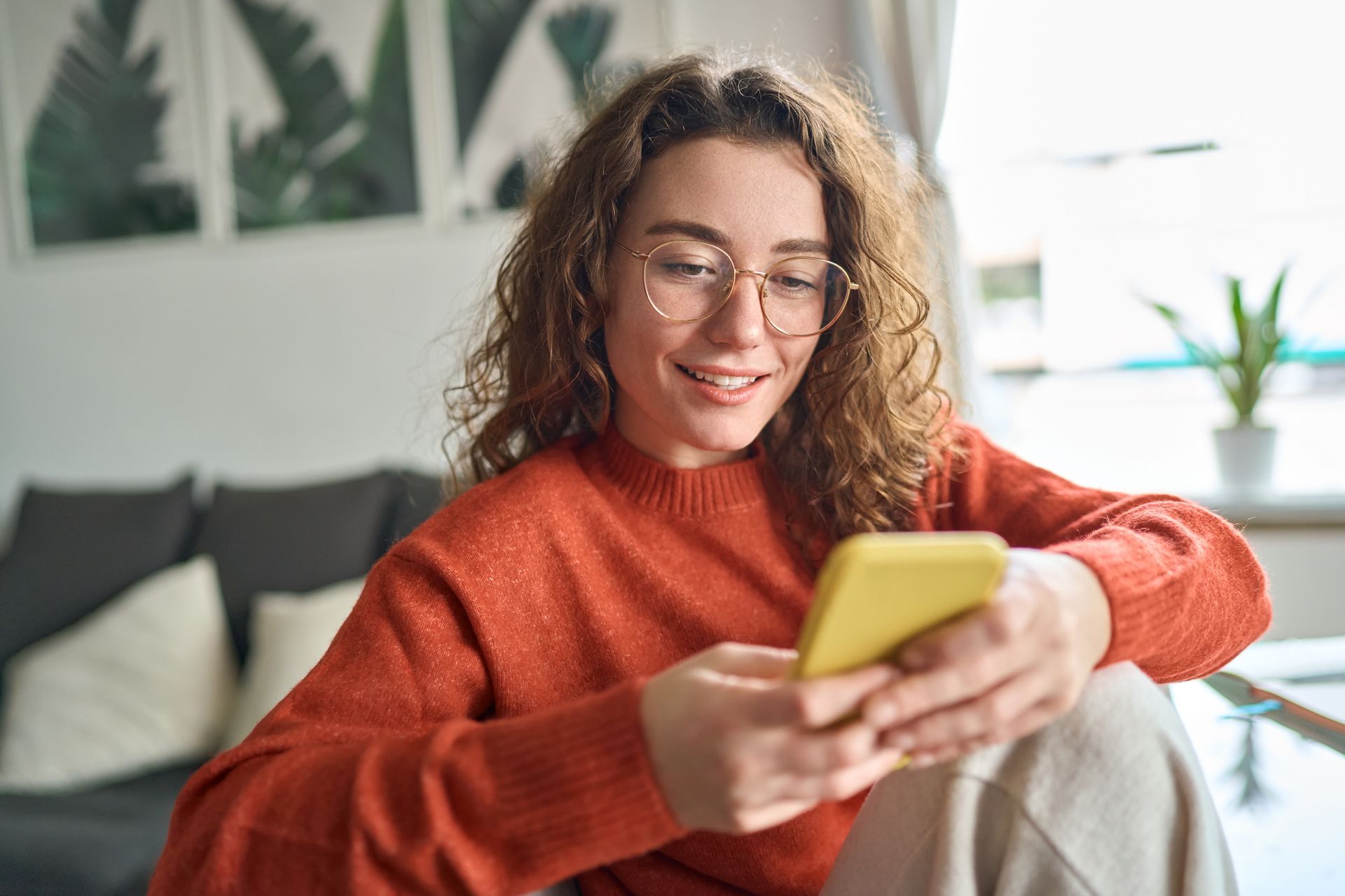 a young woman uses her smartphone to connect and engage with brands digitally