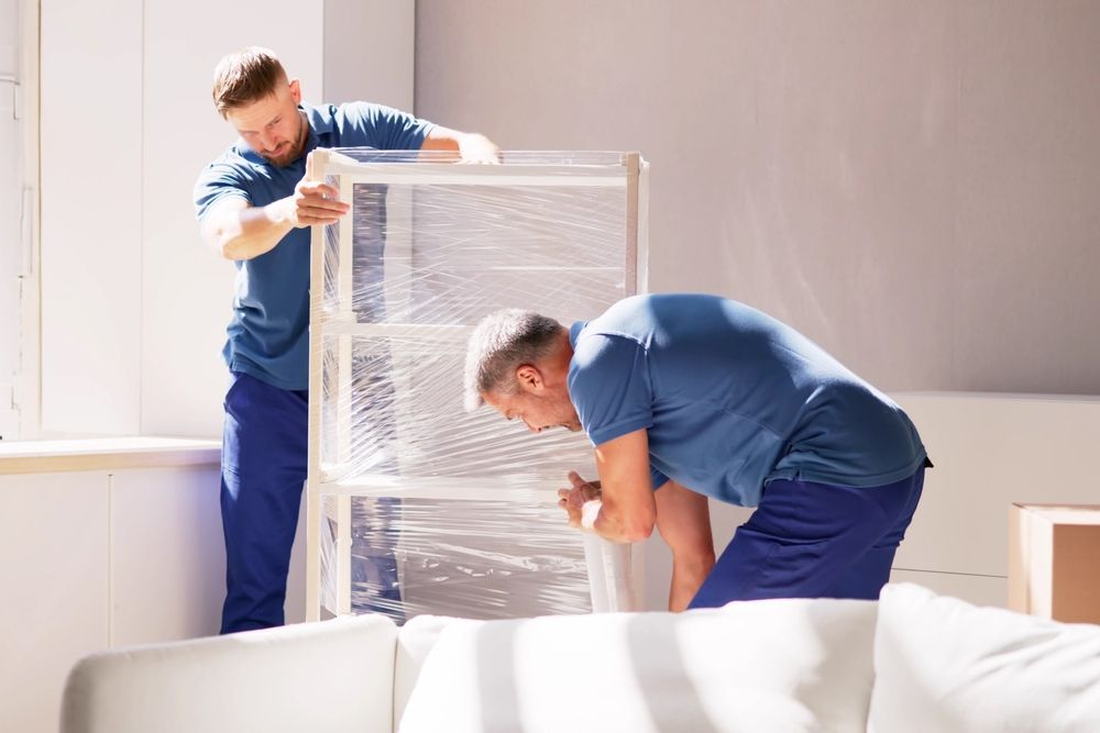Two men are moving a shelf in a living room.