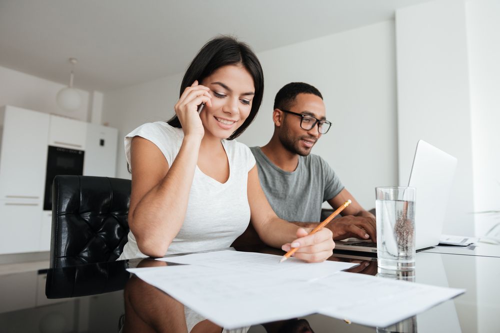 a man and a woman are sitting at a table with papers and a laptop creating a budget for 2024.