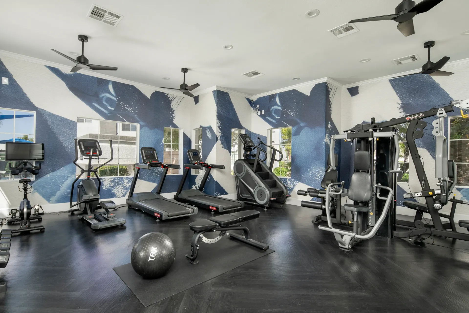 Modern gym with treadmills, stair climber, elliptical, and weight machines.