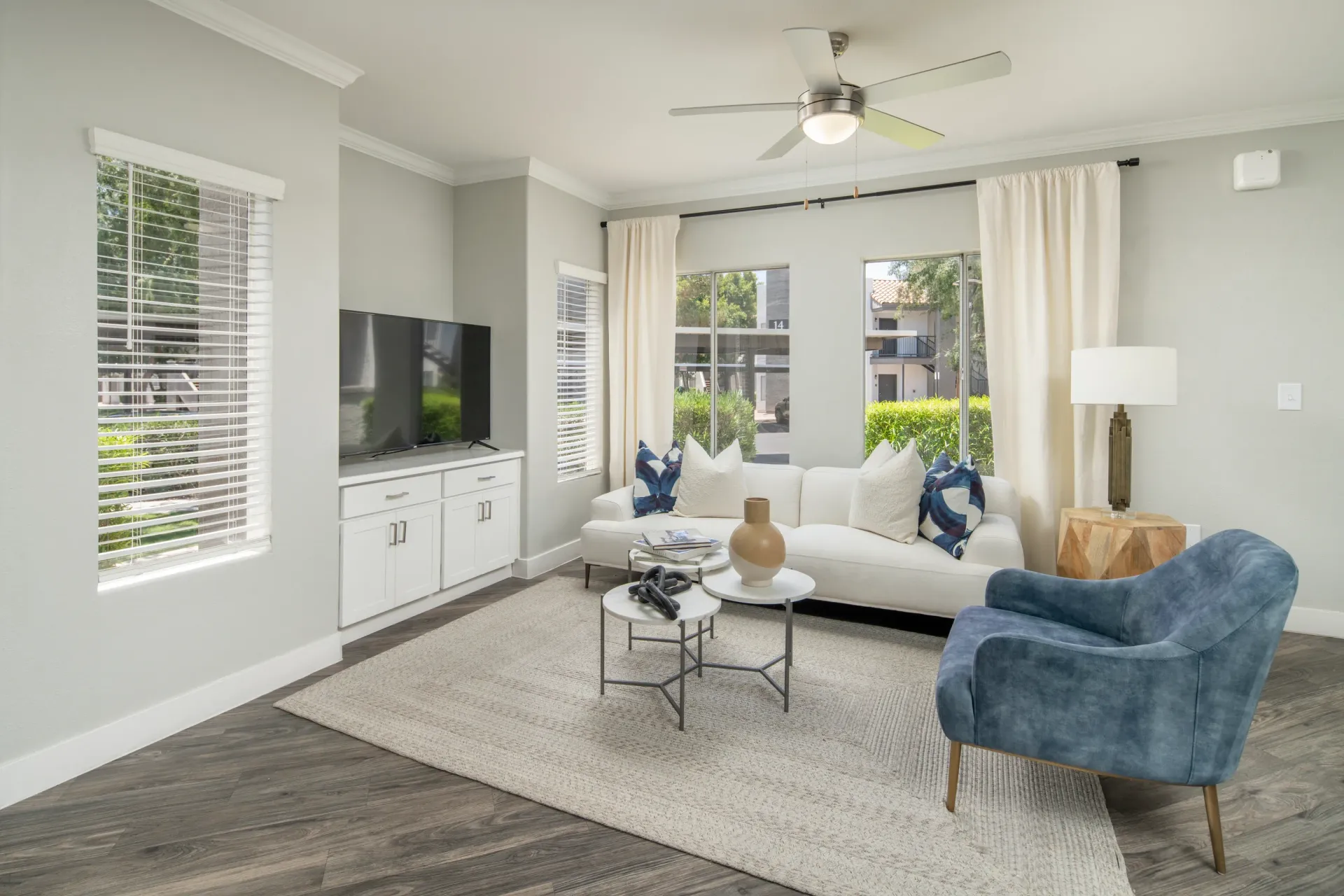Living room with a white sofa, blue accent chair, and TV.