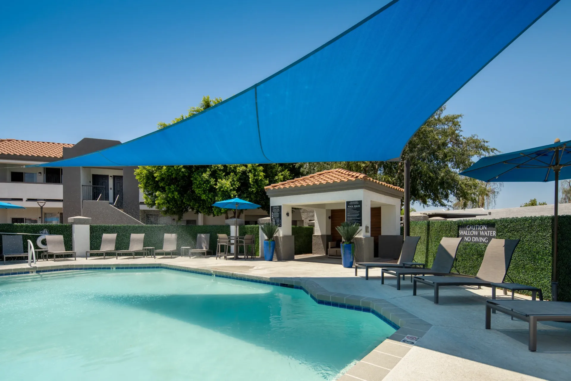 Outdoor swimming pool area with lounge chairs and a cabana.