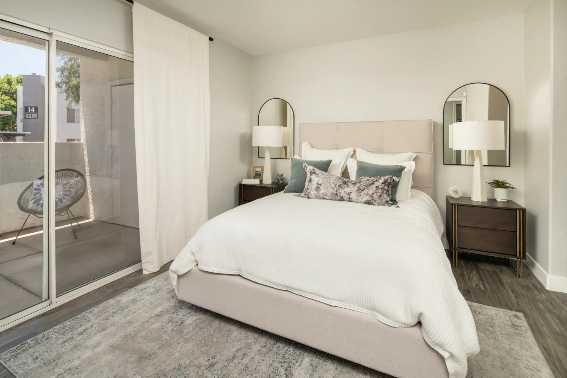 Bedroom with a king-size bed, nightstands, and a sliding glass door leading to a balcony.