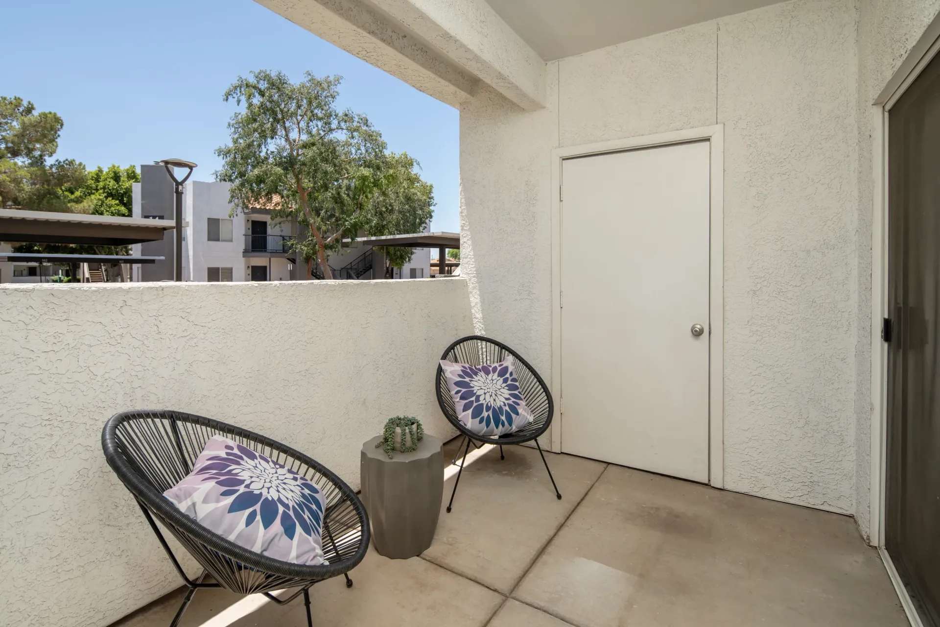 Balcony with two chairs and a small table outside an apartment unit.