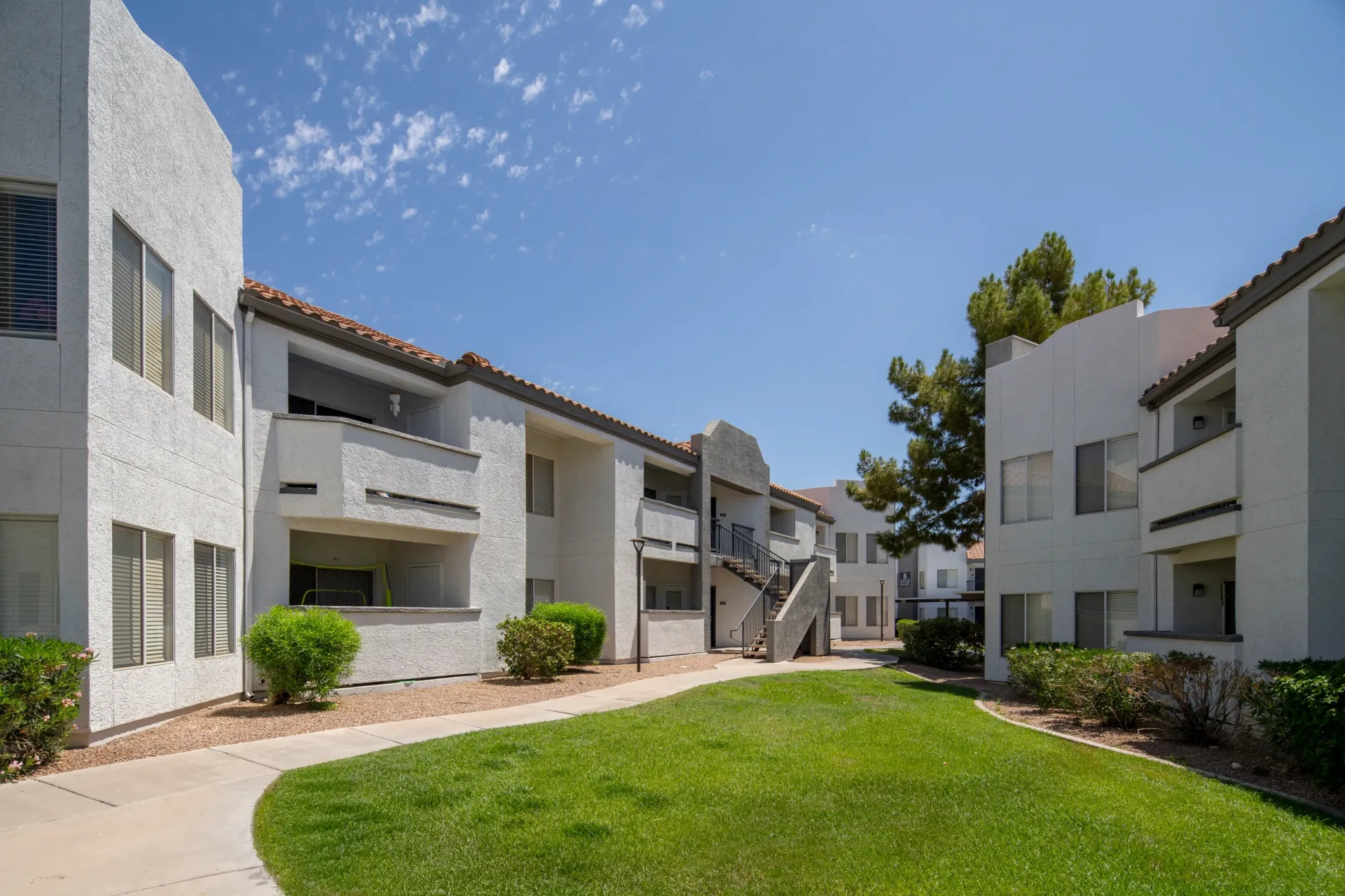 Exterior view of apartment buildings with manicured grass and walkways.