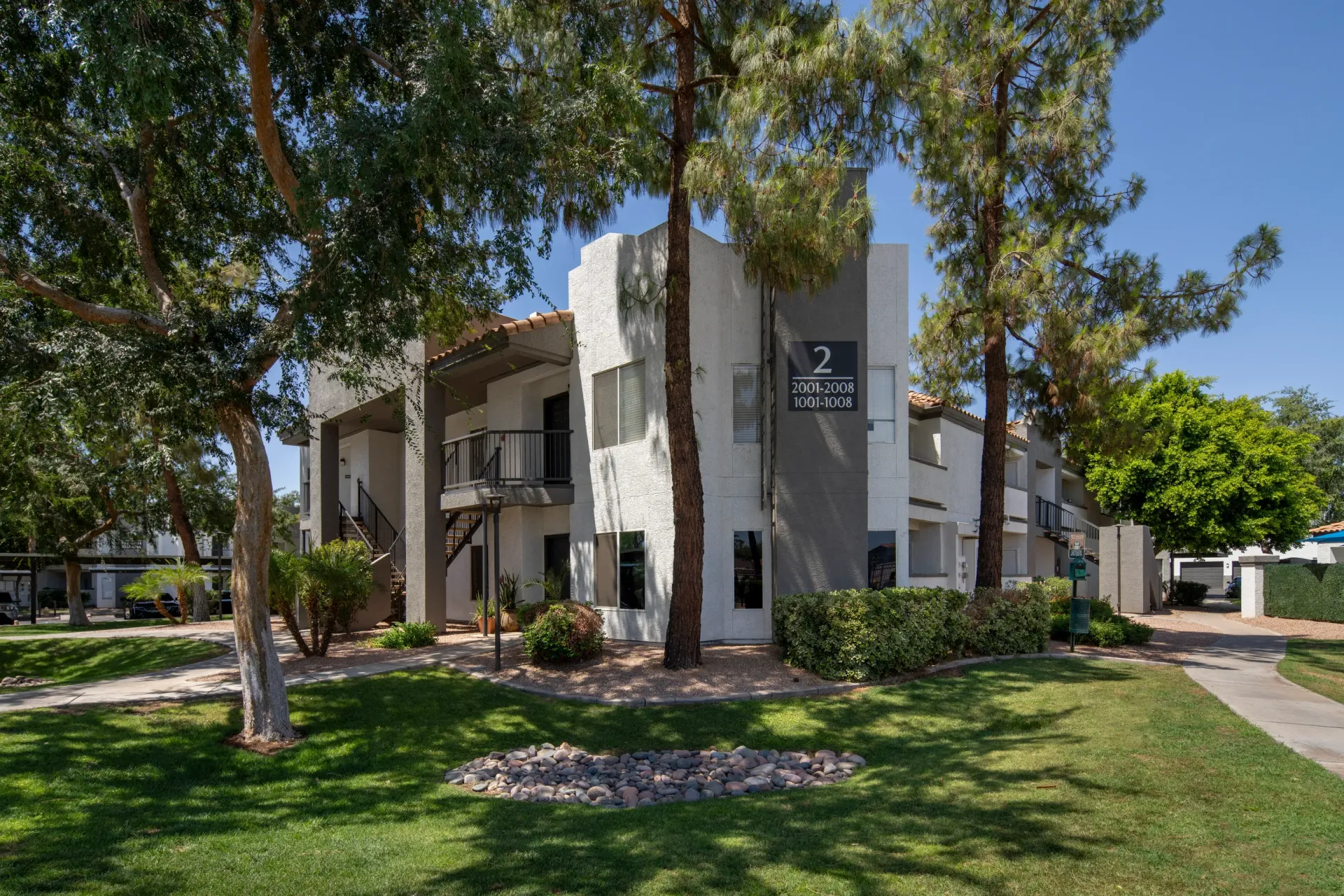 Exterior view of apartment building 2 with balconies and surrounding green lawn.
