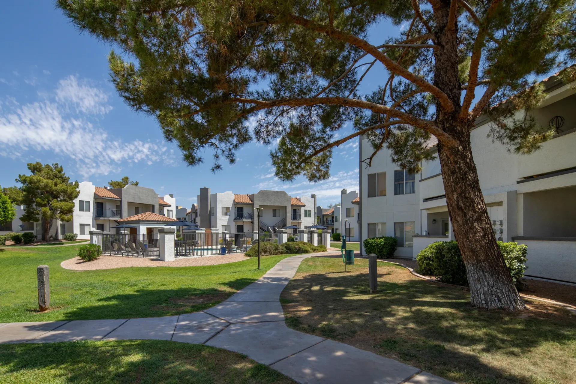 Apartment complex courtyard with a swimming pool and lounge chairs visible.