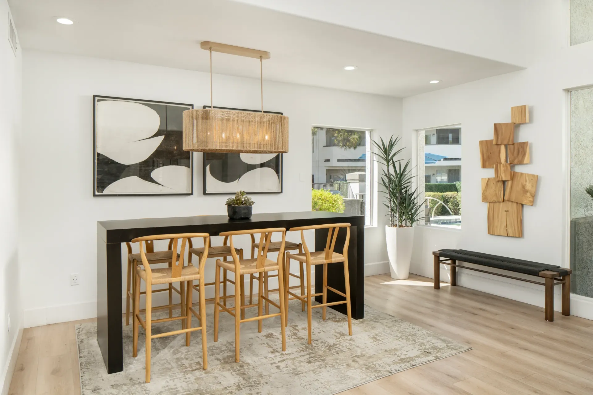 Modern dining area with a high table and stools, artwork, and plants.