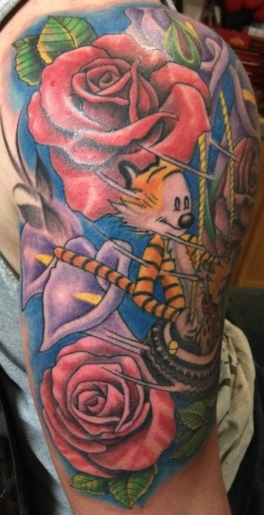 Calvin and Hobbes tattoo: Calvin riding a swing, surrounded by roses and purple flowers on a blue background.