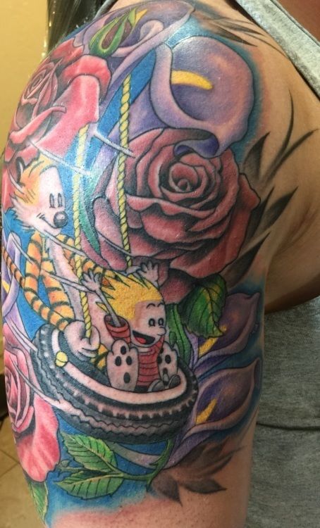Calvin and Hobbes tattoo: cartoon figures on tire swing surrounded by colorful roses and calla lilies.