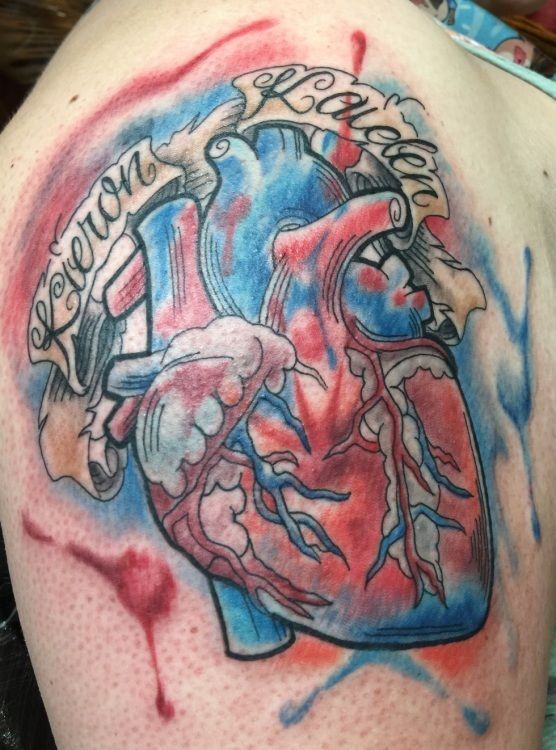 Tattoo of a human heart, red and blue with a banner that reads, 