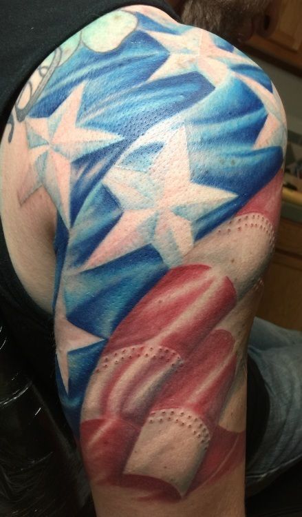 Tattoo of the American flag covering a person's upper arm. Blue stars, red and white stripes.