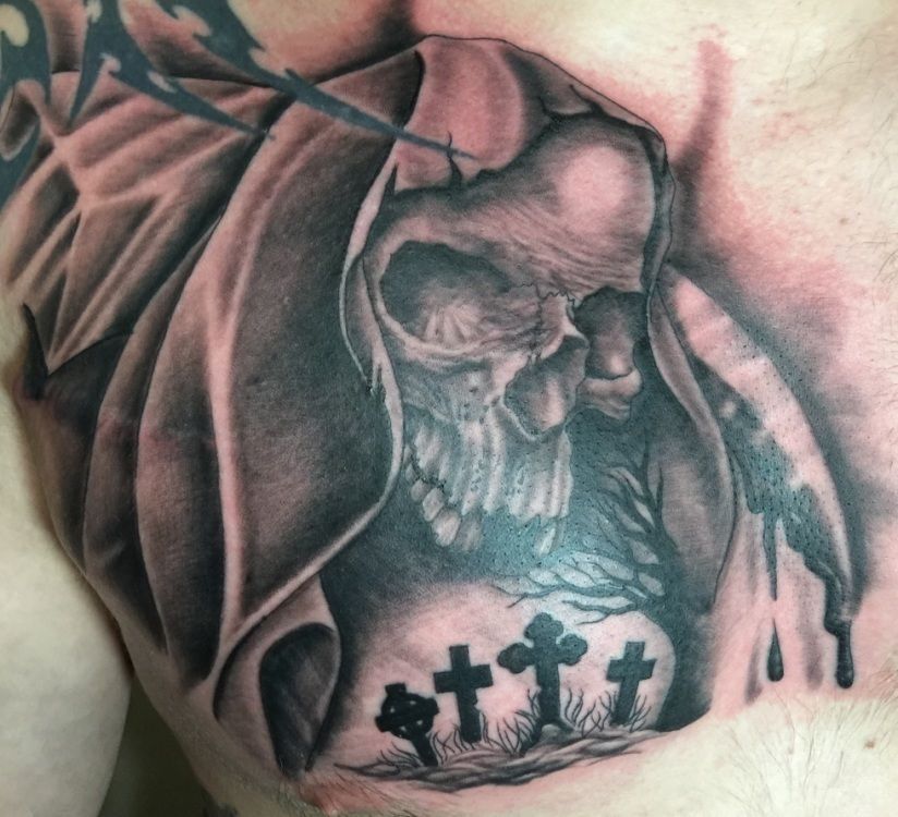 Grim reaper skull tattoo on chest with graveyard detail.