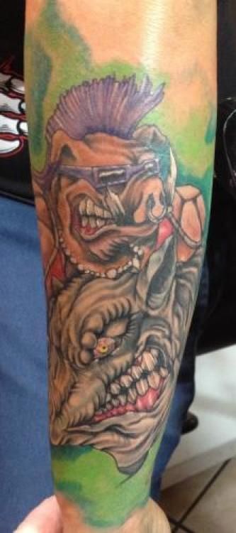 Tattoo of two aggressive pig-like characters with angry expressions, on an arm.
