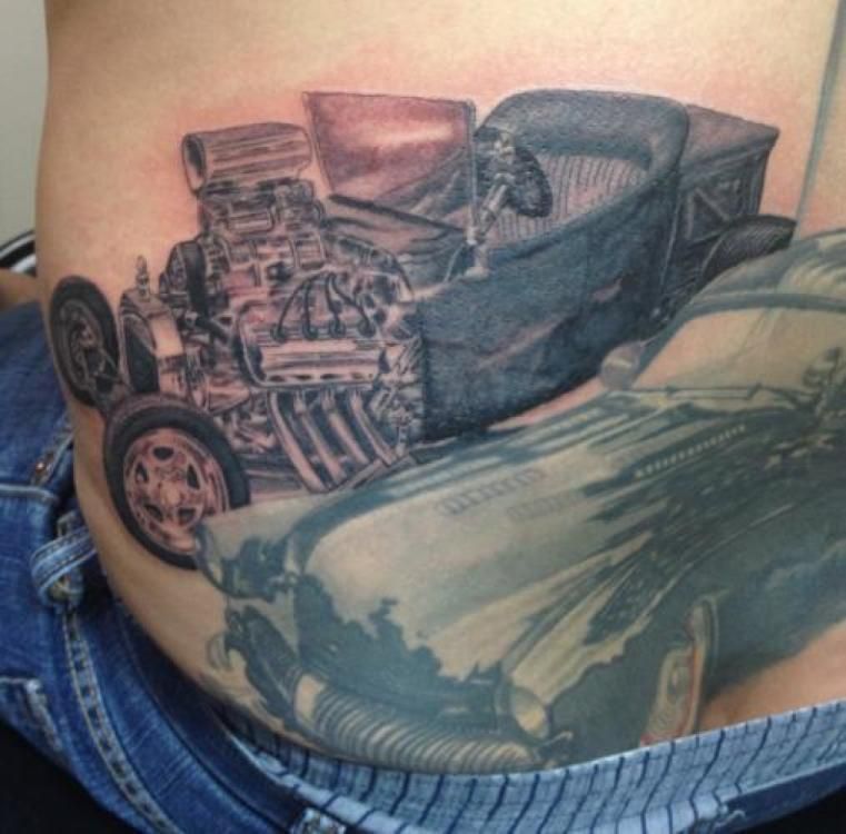 Tattoo of a hot rod car with a large engine, on a person’s torso, part of a larger design.
