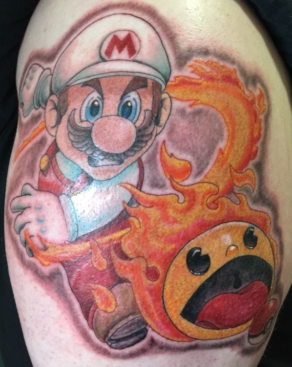 Fire Mario tattoo with a fiery Pac-Man, on skin. Mario has an angry expression.