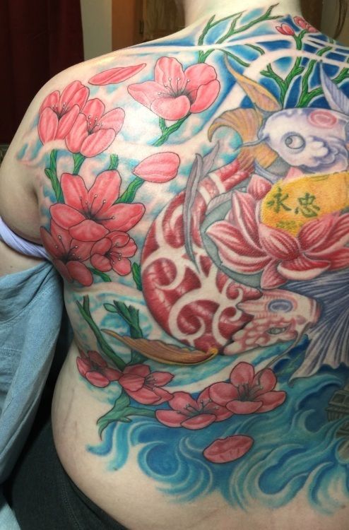 Colorful back tattoo: Koi fish swimming through water and flowers.