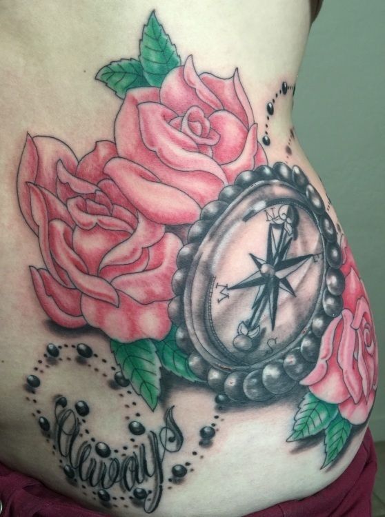 Tattoo of pink roses and a compass on a person's side; includes a rosary with the word 