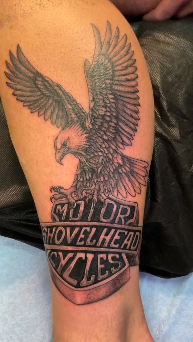 Tattoo of a bald eagle with outstretched wings above a banner reading 