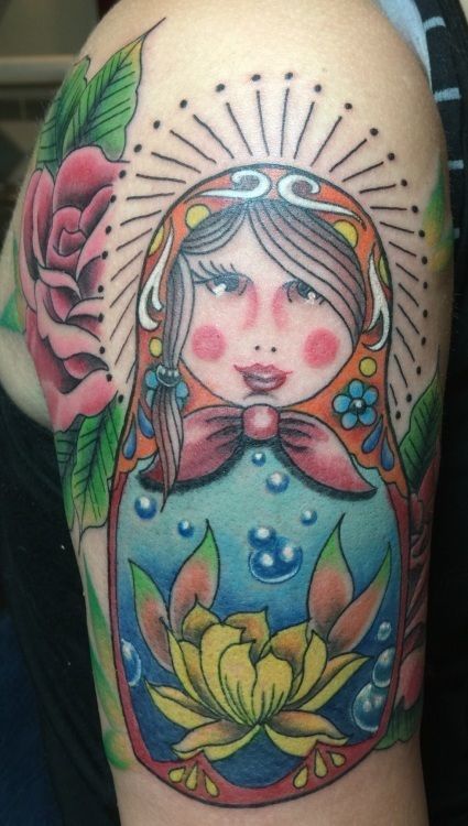 Colorful Matryoshka doll tattoo on arm with a rose.