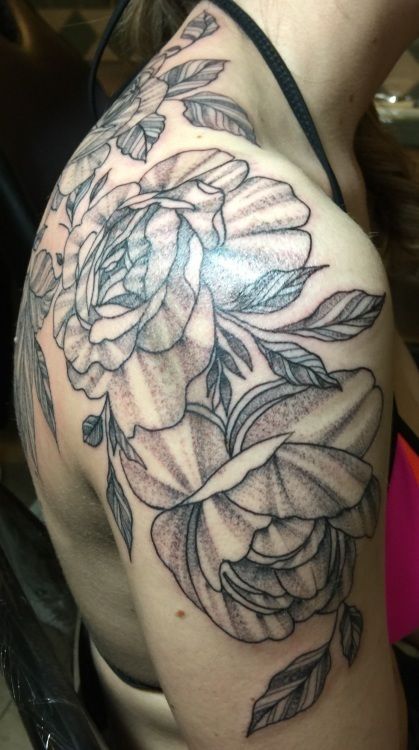 Floral tattoo design on a shoulder, featuring large flowers, leaves, and a dotted shading style.