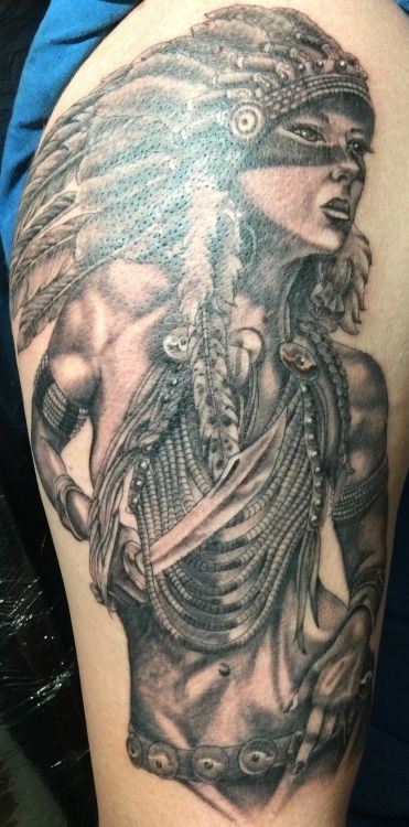Tattoo of a Native American woman with feathered headdress, looking to the side with jewelry and knife.