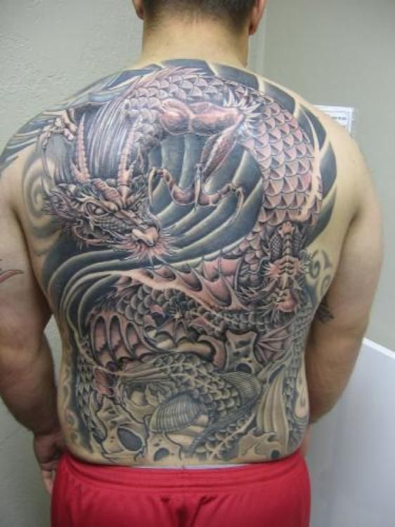 Man's back covered in a large, detailed dragon tattoo with grey and red accents.