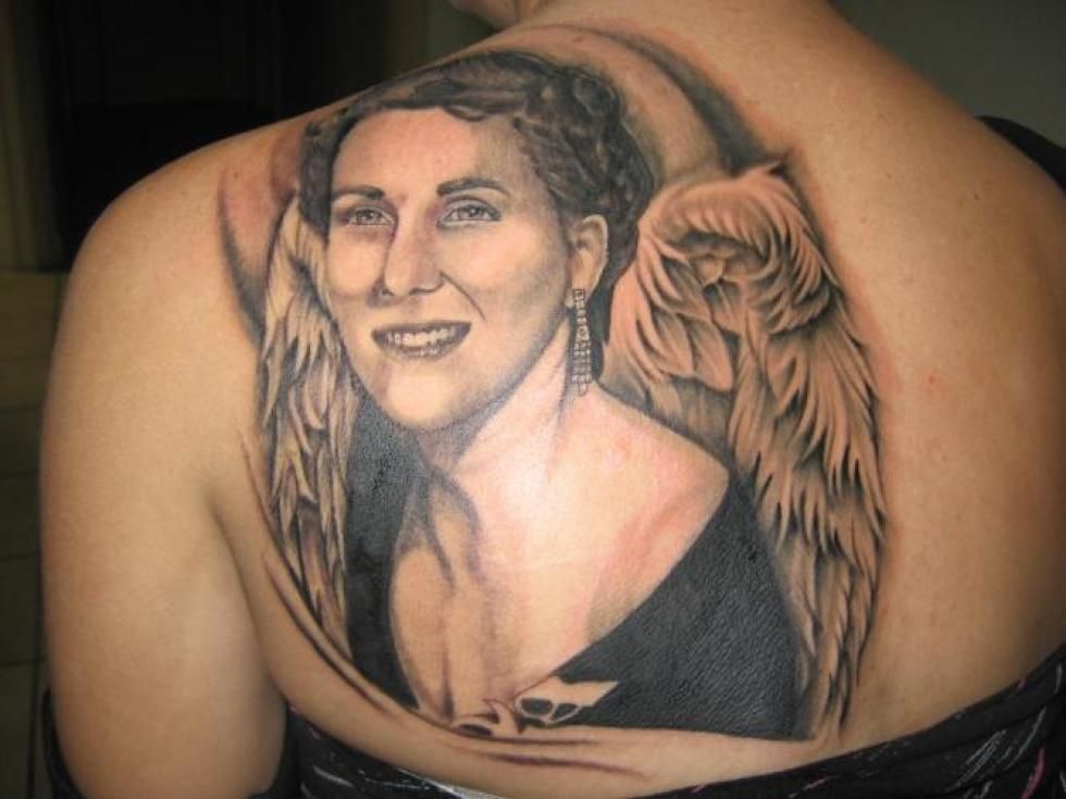 Tattoo of a person with angel wings on a back. Black and white portrait with a smiling face.