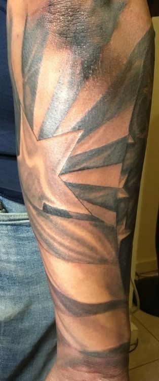 Tattoo of a starburst design on an arm. Features gray and light skin tones.