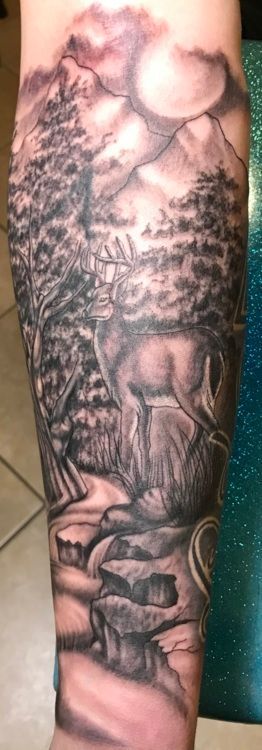 Black and gray tattoo of a deer in a forest landscape with mountains and a moon in the background.