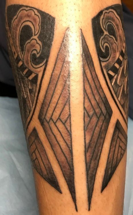 Tattoo on an arm. It features geometric shapes and wave patterns in black and gray ink.