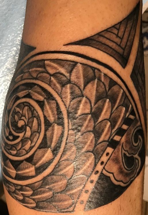 Tattoo of a stylized fish with a spiral, geometric patterns, and shaded scales on an arm.