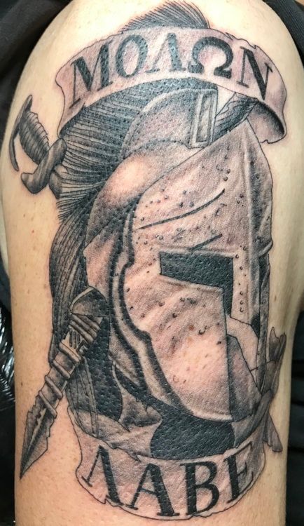 Tattoo on arm. Spartan helmet with sword, Greek text 
