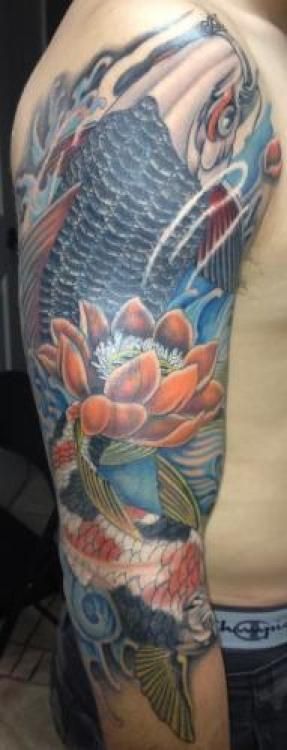 Tattoo on arm featuring a koi fish, lotus flower, and water waves in shades of blue, orange, and black.